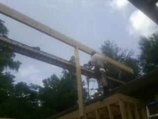 Carpenter setting a ridge beam over a new addition frame — Ice Dam Removal by Roofing Brothers in Pine City