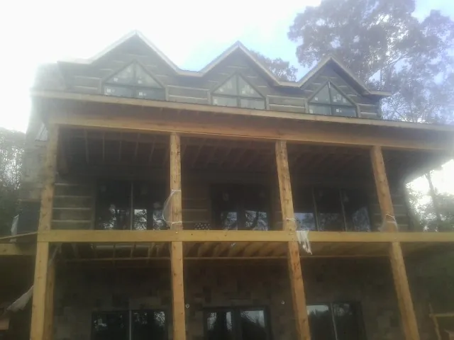 Dormers and porch framing on a large log home under construction — Roof Coating work by our crew in Pine City