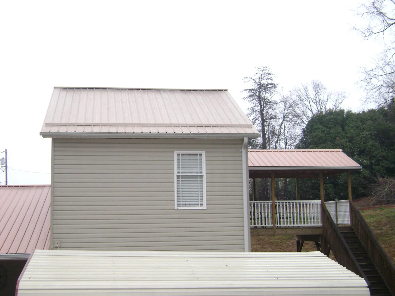 Tan metal roofs on a two story addition and attached porch, from a Roof Replacement job in Pine City