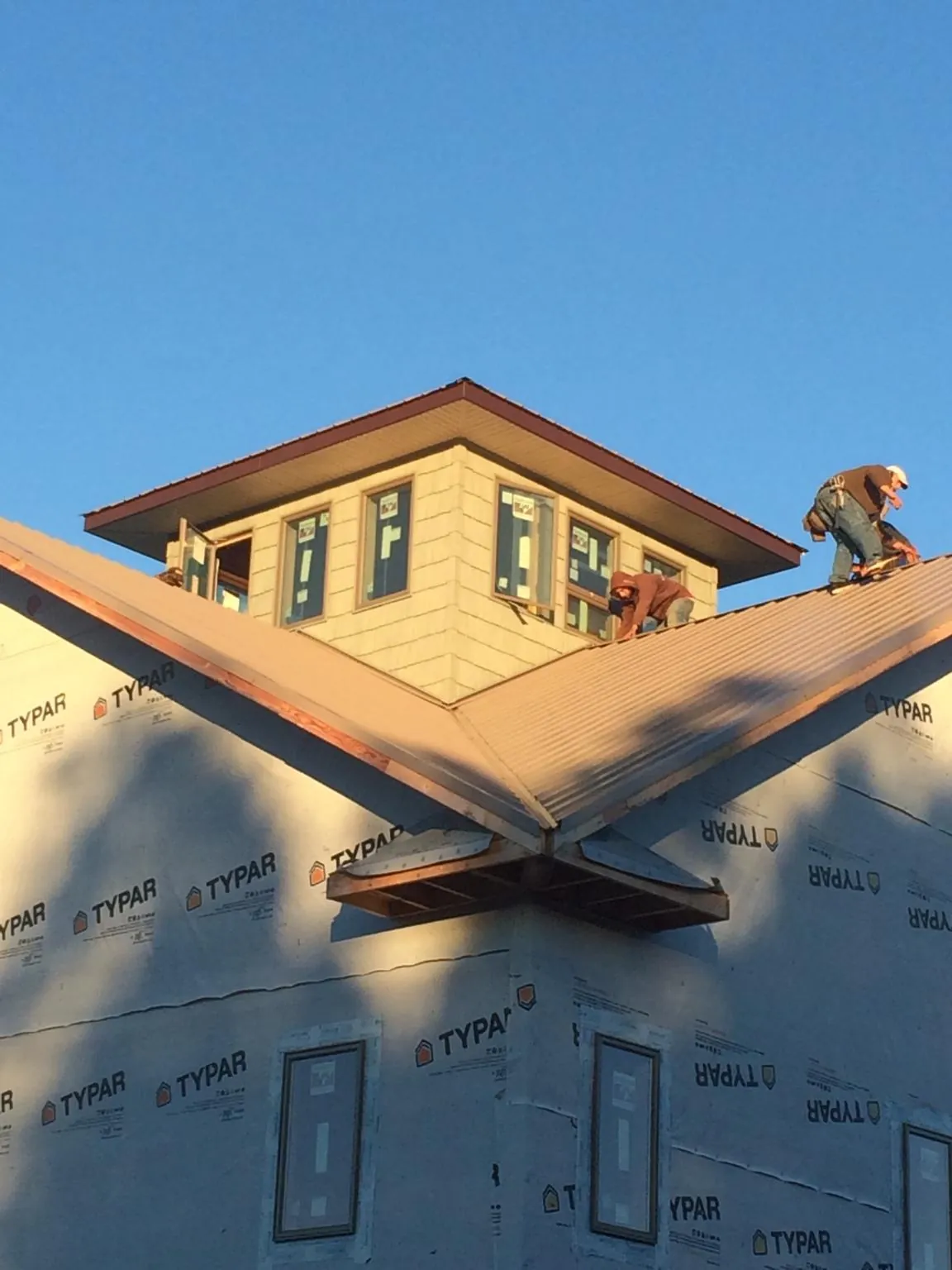 Roofers working around a rooftop cupola on a new metal roof at sunset — Roof Waterproofing in Pine City by Roofing Brothers